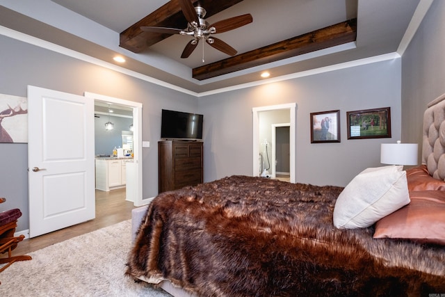 bedroom with a raised ceiling, ensuite bath, ceiling fan, and crown molding