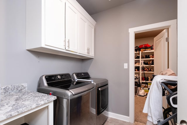 laundry room with washing machine and dryer, light colored carpet, and cabinets