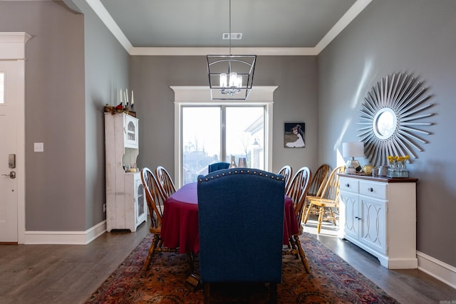 dining area featuring dark hardwood / wood-style flooring, ornamental molding, and an inviting chandelier