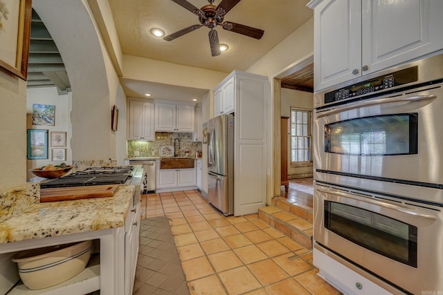 kitchen with white cabinetry, sink, stainless steel appliances, and light stone counters