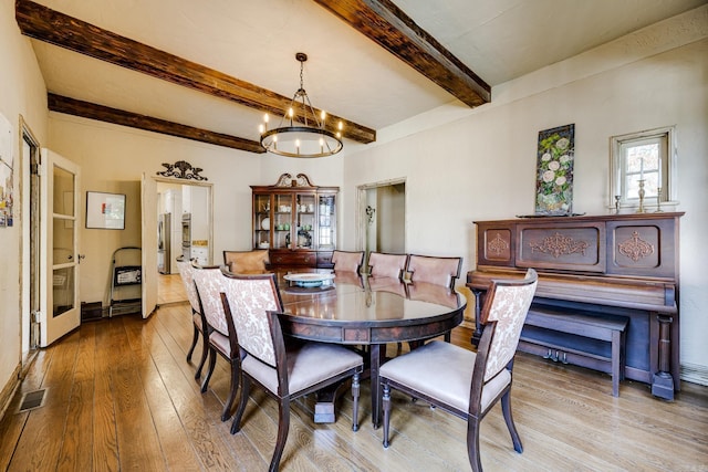 dining space with beamed ceiling, light hardwood / wood-style floors, and an inviting chandelier