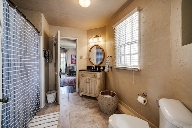 bathroom with toilet, vanity, tile patterned floors, and plenty of natural light