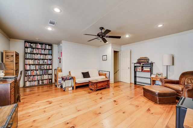 living room featuring ceiling fan, ornamental molding, and hardwood / wood-style flooring