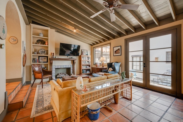 living room with french doors, ceiling fan, a tile fireplace, tile patterned flooring, and vaulted ceiling with beams