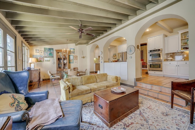 tiled living room with vaulted ceiling with beams and ceiling fan with notable chandelier