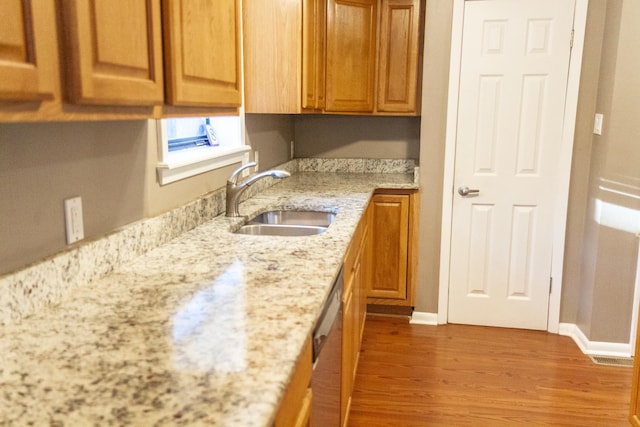 kitchen with sink, hardwood / wood-style floors, stainless steel dishwasher, and light stone countertops