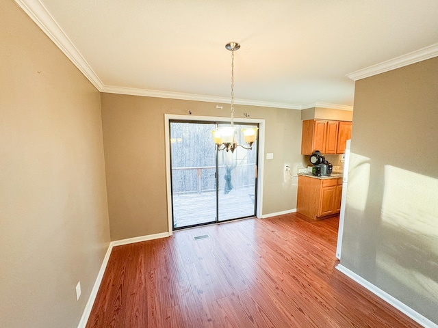 unfurnished dining area featuring light hardwood / wood-style flooring, ornamental molding, and an inviting chandelier