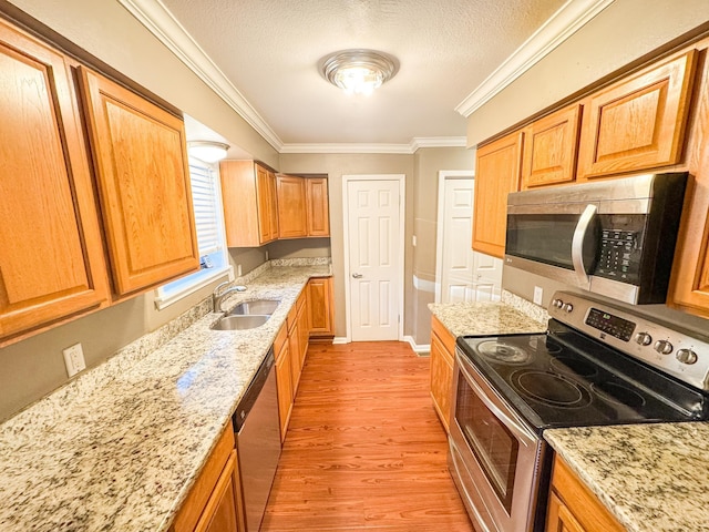 kitchen featuring sink, light stone counters, ornamental molding, and appliances with stainless steel finishes