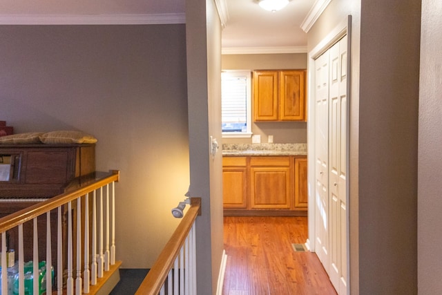 hallway featuring light wood-type flooring and ornamental molding