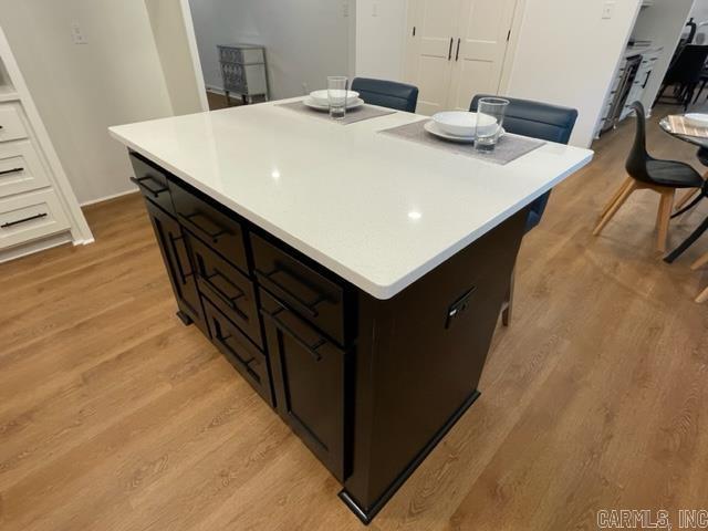 kitchen featuring dark brown cabinets, a kitchen island, and light hardwood / wood-style flooring