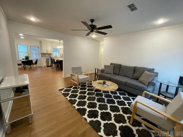 living room with ceiling fan, wood-type flooring, and ornamental molding