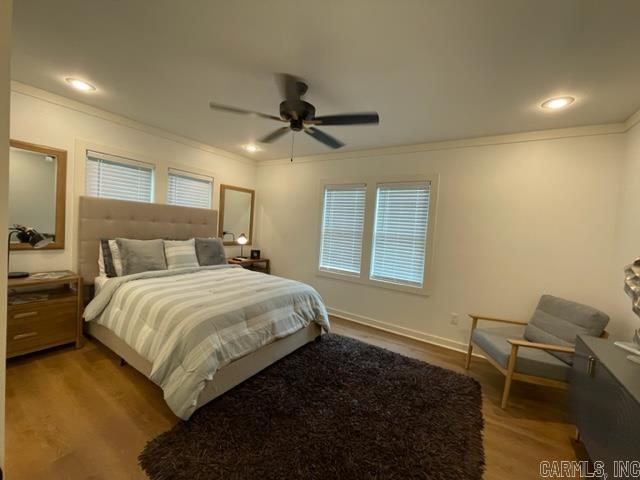 bedroom with hardwood / wood-style floors, ceiling fan, and crown molding