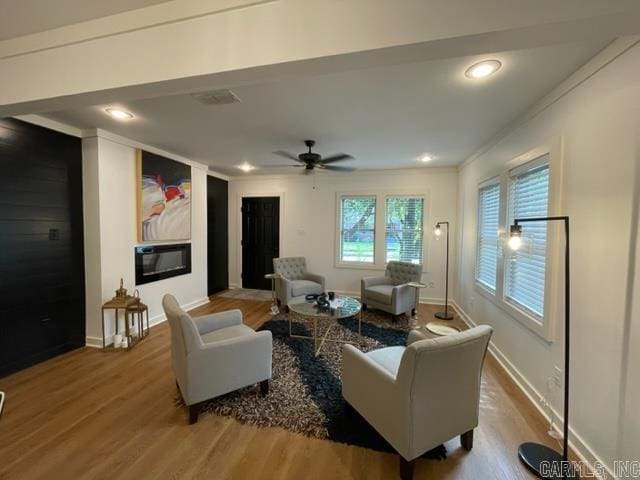 living room featuring ceiling fan, crown molding, and wood-type flooring