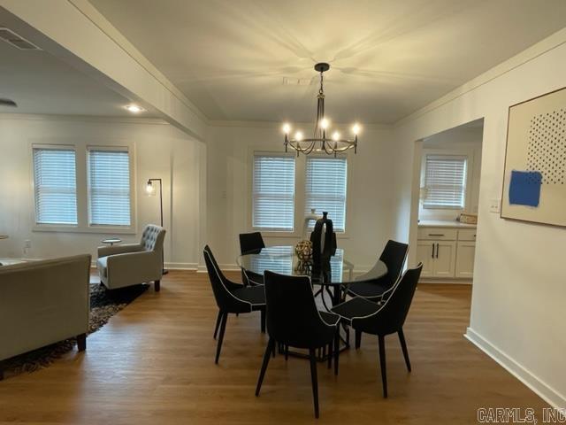 dining area with hardwood / wood-style flooring, an inviting chandelier, and ornamental molding