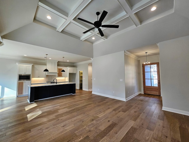 unfurnished living room with beamed ceiling, coffered ceiling, and dark hardwood / wood-style floors