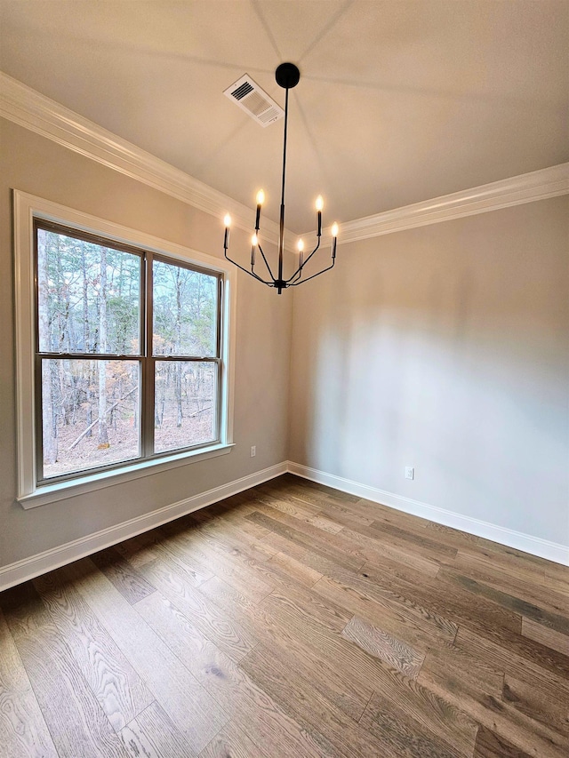 unfurnished dining area with an inviting chandelier, crown molding, and hardwood / wood-style flooring