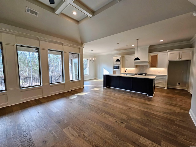 kitchen featuring pendant lighting, an island with sink, sink, white cabinets, and an inviting chandelier