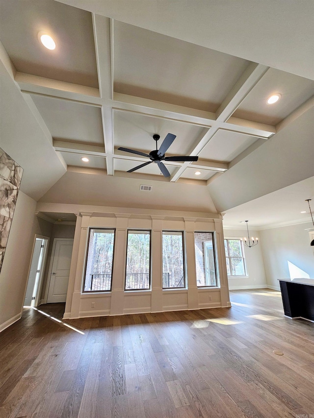 unfurnished living room featuring coffered ceiling, hardwood / wood-style flooring, beam ceiling, and ceiling fan with notable chandelier