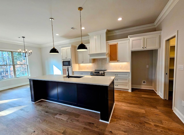 kitchen featuring white cabinetry, built in microwave, and an island with sink