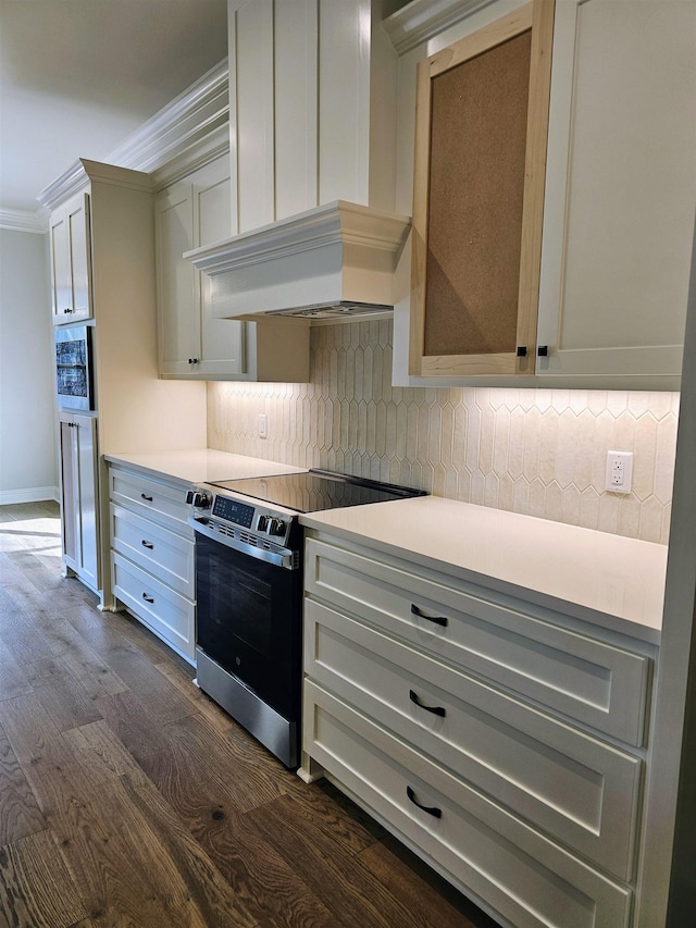 kitchen featuring premium range hood, dark hardwood / wood-style floors, decorative backsplash, ornamental molding, and electric stove