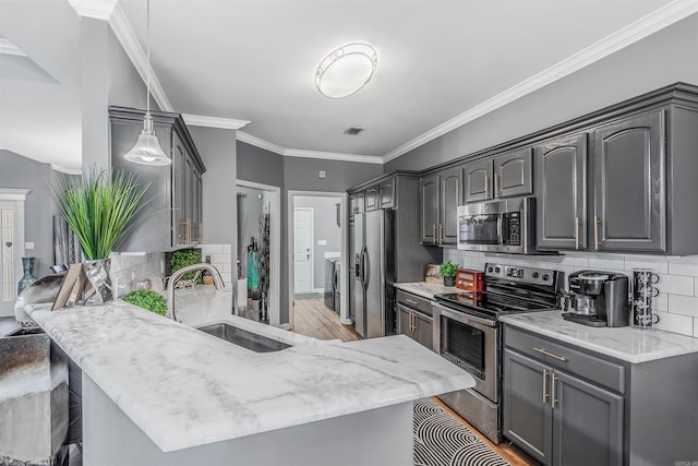 kitchen with gray cabinetry, sink, light hardwood / wood-style floors, pendant lighting, and appliances with stainless steel finishes