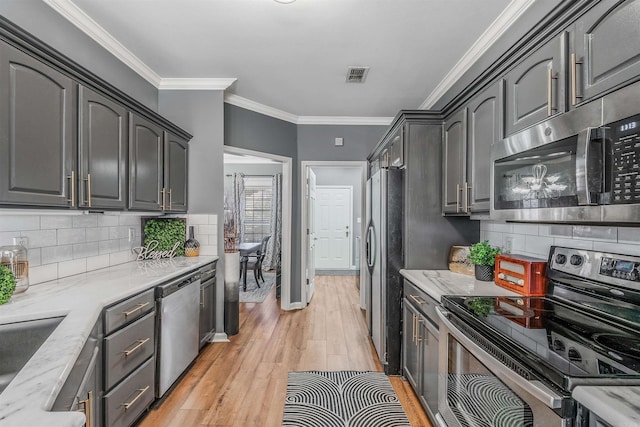 kitchen with light stone countertops, stainless steel appliances, tasteful backsplash, light hardwood / wood-style flooring, and crown molding