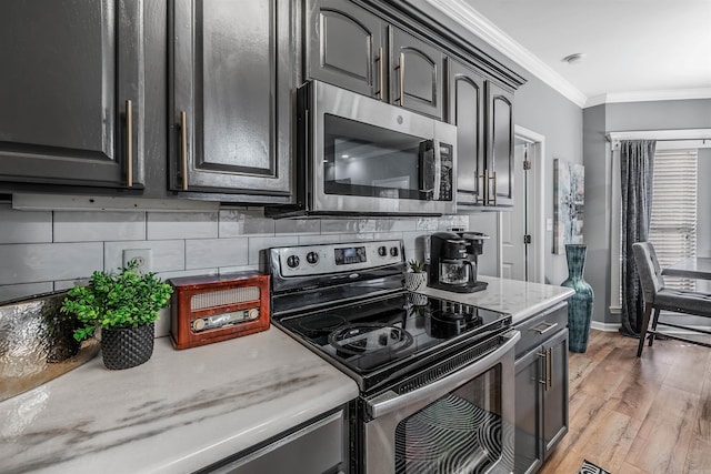 kitchen featuring light hardwood / wood-style floors, crown molding, stainless steel appliances, and tasteful backsplash