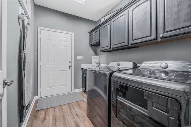 clothes washing area featuring sink, cabinets, separate washer and dryer, and wood-type flooring