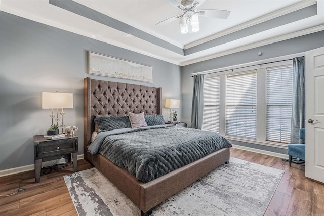 bedroom with a tray ceiling, crown molding, ceiling fan, and hardwood / wood-style flooring