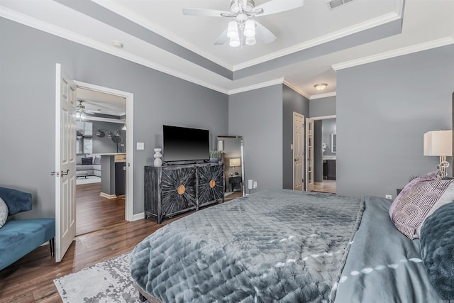 bedroom featuring ornamental molding, a raised ceiling, ceiling fan, connected bathroom, and dark hardwood / wood-style floors