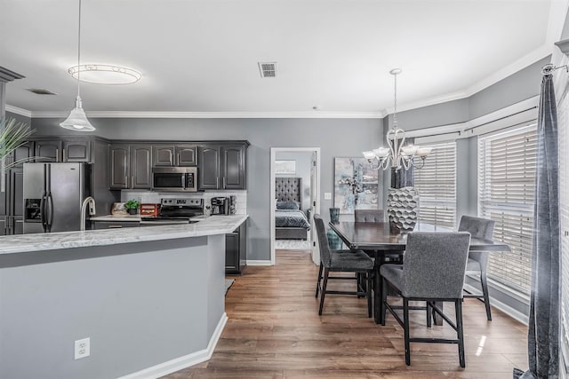 kitchen featuring dark brown cabinetry, a wealth of natural light, stainless steel appliances, tasteful backsplash, and decorative light fixtures