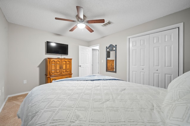 carpeted bedroom featuring ceiling fan, a closet, and a textured ceiling