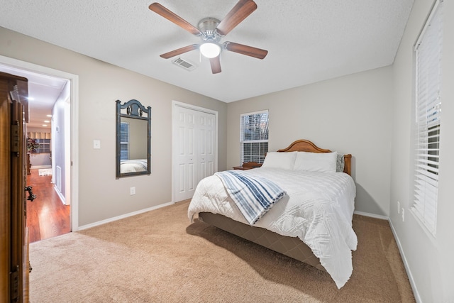 carpeted bedroom featuring ceiling fan, a textured ceiling, and a closet