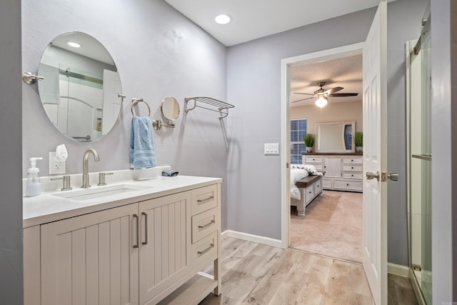 bathroom with hardwood / wood-style flooring, ceiling fan, a shower with shower door, and vanity