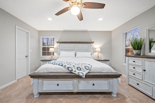 bedroom with a textured ceiling, light colored carpet, and ceiling fan