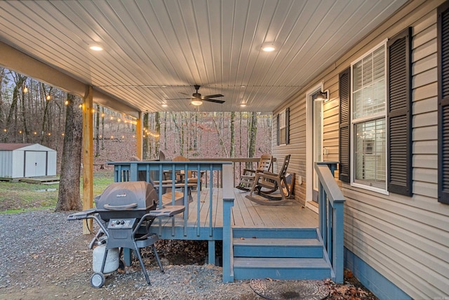 wooden terrace with ceiling fan, a storage shed, and a grill