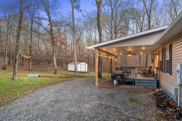 view of yard with ceiling fan, a storage unit, and a deck