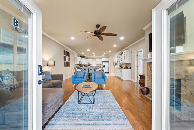 living room featuring ceiling fan, light hardwood / wood-style floors, and ornamental molding