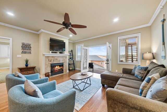 living room with a high end fireplace, hardwood / wood-style floors, and ornamental molding