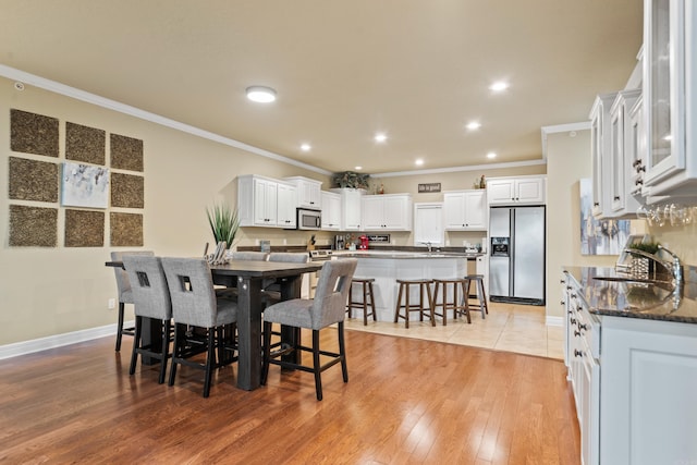 dining space featuring light hardwood / wood-style flooring, ornamental molding, and sink