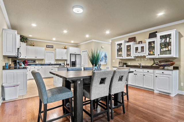 dining space with crown molding, sink, and light hardwood / wood-style flooring