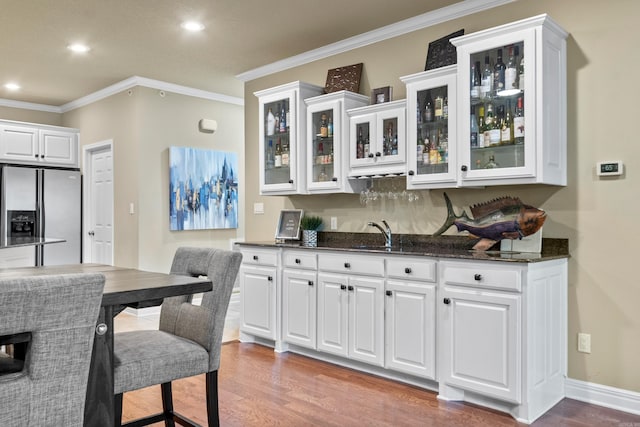 kitchen with white cabinetry, sink, stainless steel fridge, crown molding, and hardwood / wood-style flooring