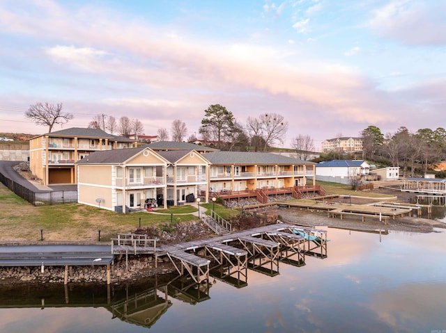 back house at dusk featuring a water view and a yard