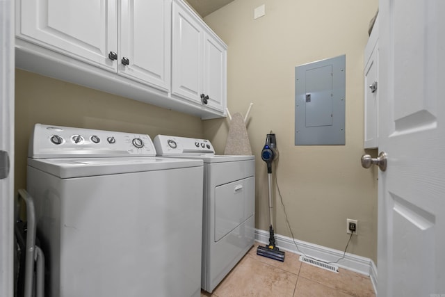 clothes washing area featuring electric panel, separate washer and dryer, light tile patterned floors, and cabinets