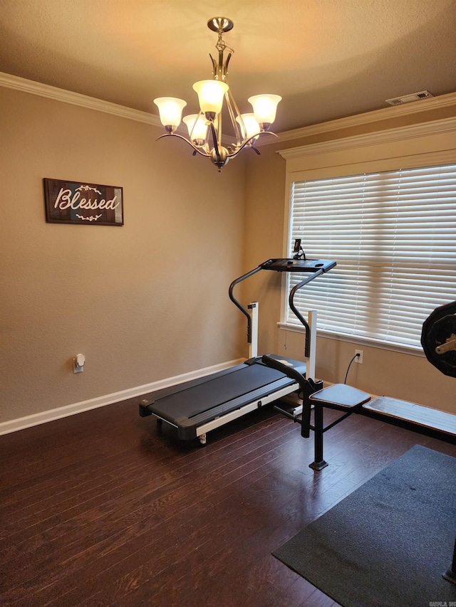 exercise room featuring dark hardwood / wood-style flooring, an inviting chandelier, and ornamental molding