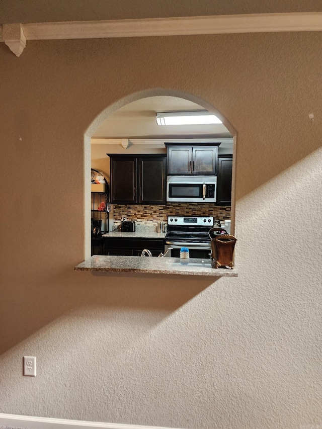 kitchen featuring decorative backsplash, light stone counters, ornamental molding, and appliances with stainless steel finishes