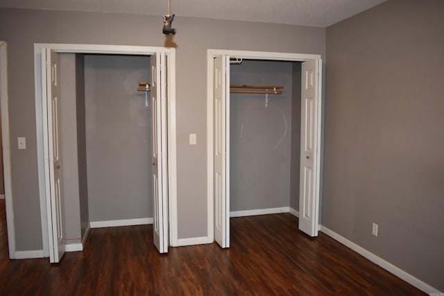 unfurnished bedroom with dark wood-type flooring and a closet