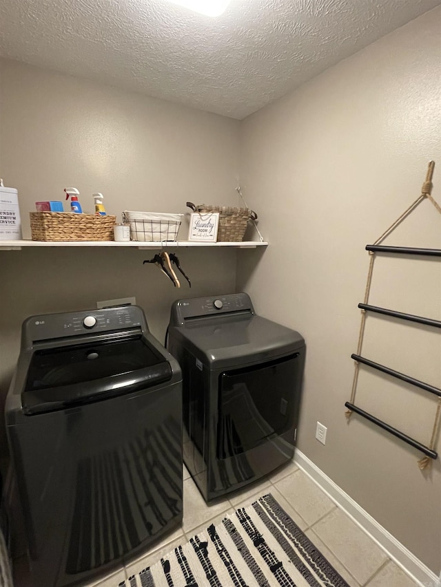 laundry area with separate washer and dryer, light tile patterned floors, and a textured ceiling