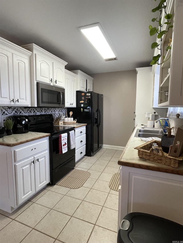 kitchen with white cabinetry, sink, tasteful backsplash, light tile patterned floors, and black appliances