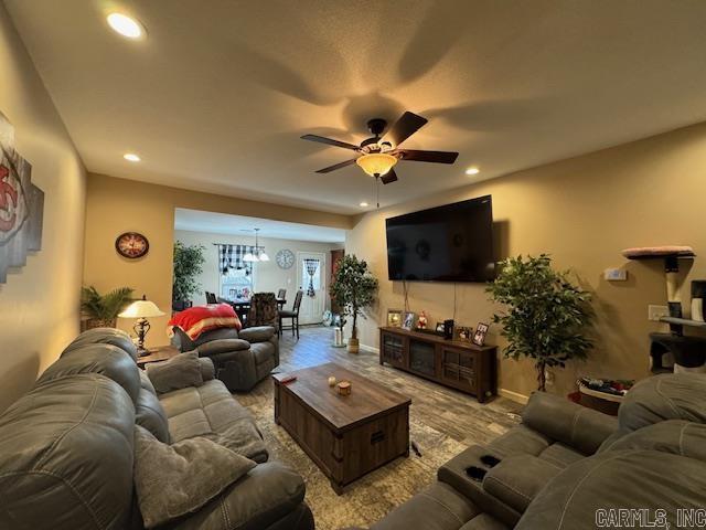 living room featuring ceiling fan with notable chandelier